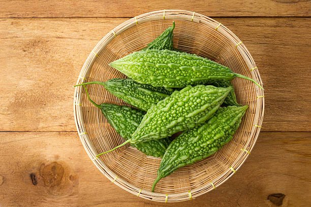 Top view of green bitter gourds in the basket on wood background.