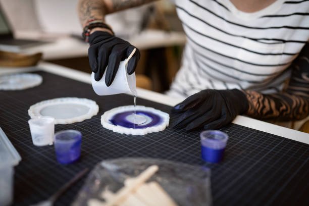 Creative young Caucasian woman, making epoxy jewlery, while pouring resin into silicone mold